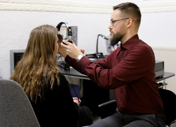 Hörtest beim Akustiker: Ein Experte prüft das Gehör einer Frau mit Kopfhörern.